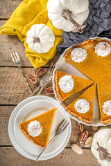 Traditional Autumn Pumpkin Pie. Homemade American Pumpkin pie topped with Whipped Cream. Rustic wooden table bakcground with Cozy plaid and sweater.