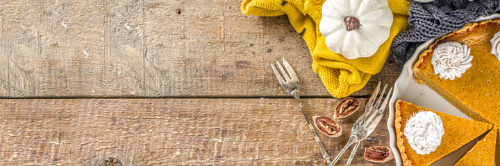 Traditional Autumn Pumpkin Pie. Homemade American Pumpkin pie topped with Whipped Cream. Rustic wooden table bakcground with Cozy plaid and sweater.