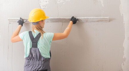 Construction worker usually levels concrete walls with plaster, preparing for painting