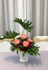 Red and orange roses in white vase on the table.