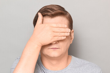 Portrait of serious mature man covering eyes with one hand