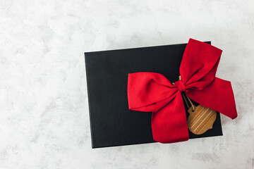 Regalo en caja negra y lazo rojo con fondo en blanco 