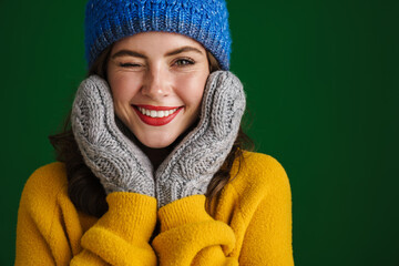 Beautiful happy girl in knit hat and mittens winking at camera