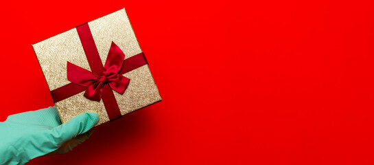 Gift box, hand in medical gloves. Preparation for the holiday during the coronavirus pandemic.