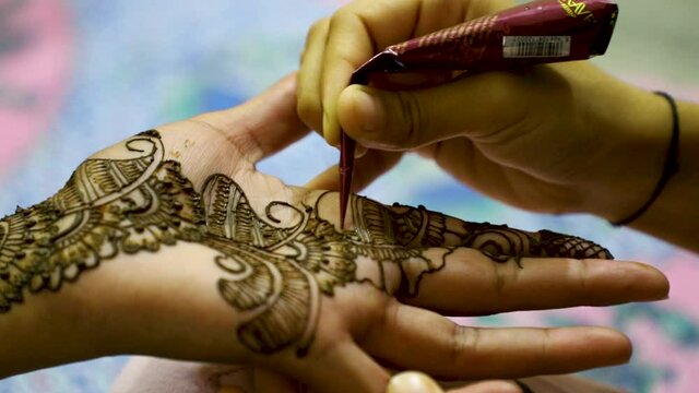Closeup of Woman hand designing Henna or Mehendi during indian wedding.