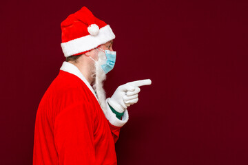 Fototapeta na wymiar Side view Santa Claus man wears face mask shows to copy space coronavirus virus covid-19 during quarantine.