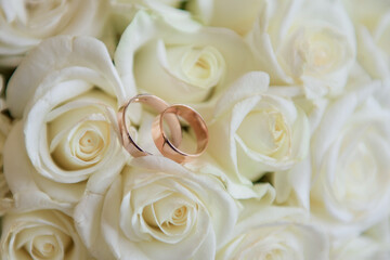 Gold wedding rings lie on the bouquet for the bride. Wedding rings in a rose. Wedding accessories
