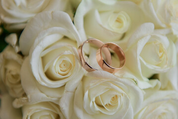 Gold wedding rings lie on the bouquet for the bride. Wedding rings in a rose. Wedding accessories
