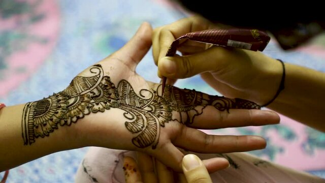 Closeup of Woman hand designing Henna or Mehendi during indian wedding.