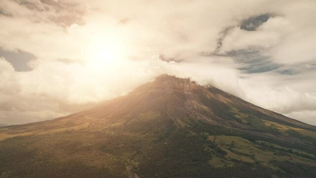 Aerial volcano erupt at sun light closeup. Nobody nature landscape at Legazpi town, Mayon mount, Philippines, Asia. Cinematic soft sunlight at green exotic plants, grasses at mountain hills