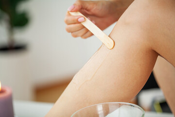 Beautician waxing female legs in spa center