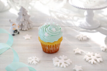 Obraz na płótnie Canvas Christmas cupcakes with mint blue cream and white snowflakes on Christmas decoration table. クリスマススノーフレークカップケーキ