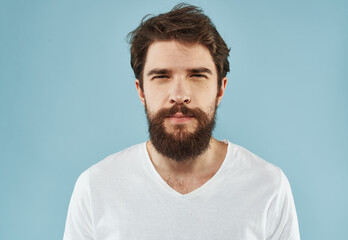 Fototapeta premium Handsome man with a beard on a blue background white t-shirt portrait