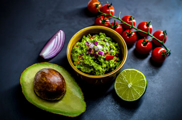 Delicious bowl of traditional Mexican Guacamole, ingredients: Avocado, onion, tomatoes and lime Fresh, raw, vegetarian dish