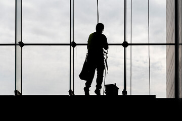 Fototapeta na wymiar Worker silhouettes cleaning building facade window glass