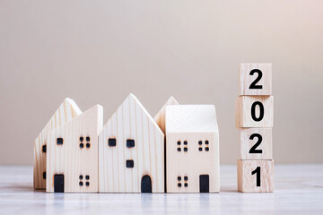 2021 Happy New Year with house model on table wooden background. Banking, real estate, investment,...