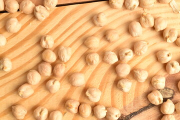 Uncooked hummus grains, close-up, on a wooden table.