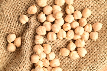 Uncooked hummus seeds, close-up, on jute fabric.