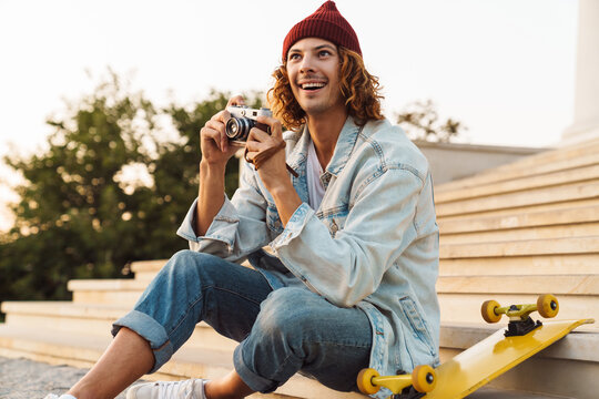 Happy young curly man scater holding camera
