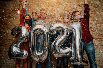 Happy group of friends with face mask celebrating new 2021 year - Confetti falling in the air -...