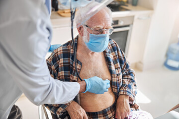 Geriatrician auscultating the heart and the lungs of the patient