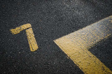 sign on the asphalt, yellow painted number seven on grey street, yellow lines like a corner on the...