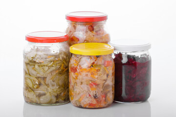 Glass jars of pickled homemade organic cucumber carrrot with garlic and red cabbage vegetables  isolated on white background 