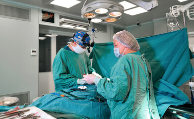 Surgeon and his assistant performing cosmetic surgery on nose in hospital operating room. Nose...