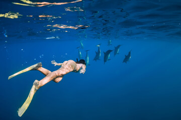 Young woman swim with dolphins in ocean