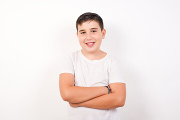 Caucasian young boy standing against white background  being happy smiling and crossed arms looking confident at the camera. Positive and confident person.