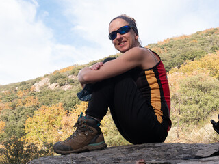 BLOND WOMAN HIKING WITH GLASSES, SITTING IN THE MOUNTAIN