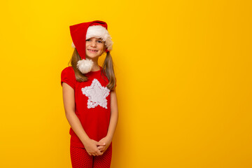 Kid wearing Santa hat isolated on yellow colored background