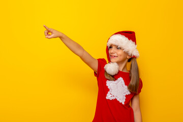 Child wearing Santa hat pointing towards blank space