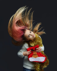 young girl in a Santa hat holds a Christmas stocking. photo session in the Studio on a gray background