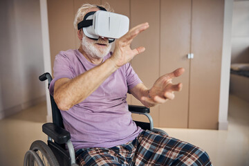 Elderly gamer in VR goggles sitting in the wheelchair