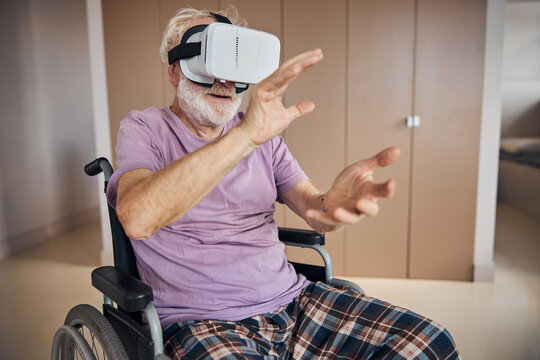 Elderly gamer in VR goggles sitting in the wheelchair