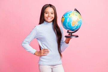 Portrait of lovely cheerful girl holding in hands globe college lesson isolated over pink pastel color background