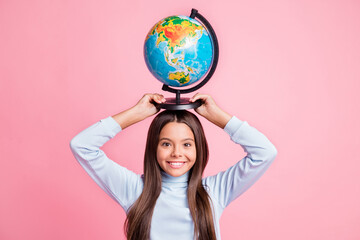 Portrait of lovely cheerful smart funny girl carrying globe on head lesson isolated over pink pastel color background