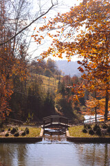 Obraz premium Golden autumn in the mountains among the trees, hills and overlooking the bridge over the lake