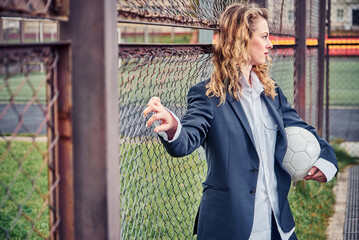 portrait of beautiful young woman with ball near goal net at stadium