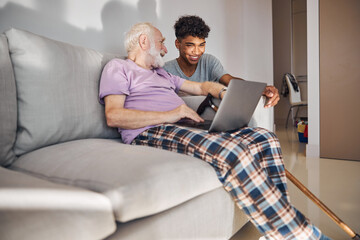 Smiling pensioner with a laptop looking at a young man