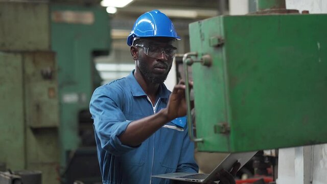 Male Engineer Working on digital tablet in Factory. black male engineer checking Quality control the condition of the machine