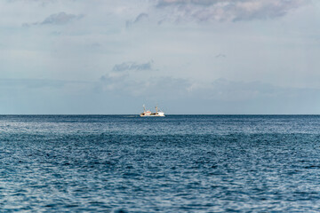 Blick auf die ruhige See. Ein Schiff fährt am Horizont.