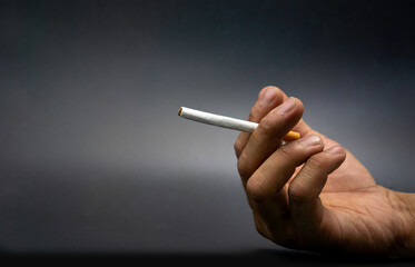 Hand of a man who grabs a cigarette without light, World No Tobacco Day concept