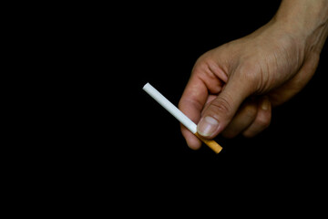 A young man's hand holds an unlit cigarette. As a reminder of how to quit smoking because it is a bad thing, the World No Tobacco Day concept.
