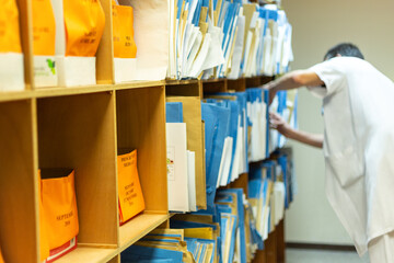 Recherche dossier médical aux archives patient personnel hospitalier blouse blanche