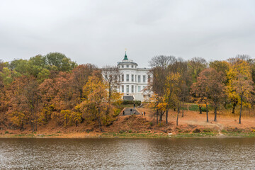 Fototapeta na wymiar Panoramic autumn view of the view of the Bogoroditsky palace and park in Bogoroditsk. Autumn fantastic view of the palace with orange-yellow trees in the park.