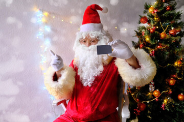 elderly santa claus in a suit, with a white beard congratulates children and adults, holds a blank credit card in his hand, concept of christmas, holiday discounts, shopping, gifts