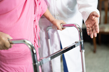 Doctor help and care Asian senior or elderly old lady woman use walker with strong health while walking in hospital.