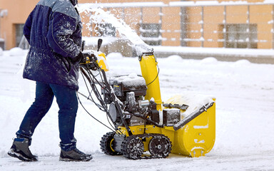 Worker with track drive snowthrower removing deep snow, heavy duty assistant for snow and ice...
